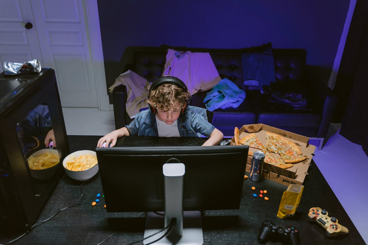 A young boy plays video games at home, surrounded by snacks, showcasing the gaming lifestyle.